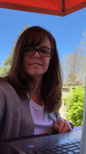 Heather works at her laptop on a sunny backyard patio